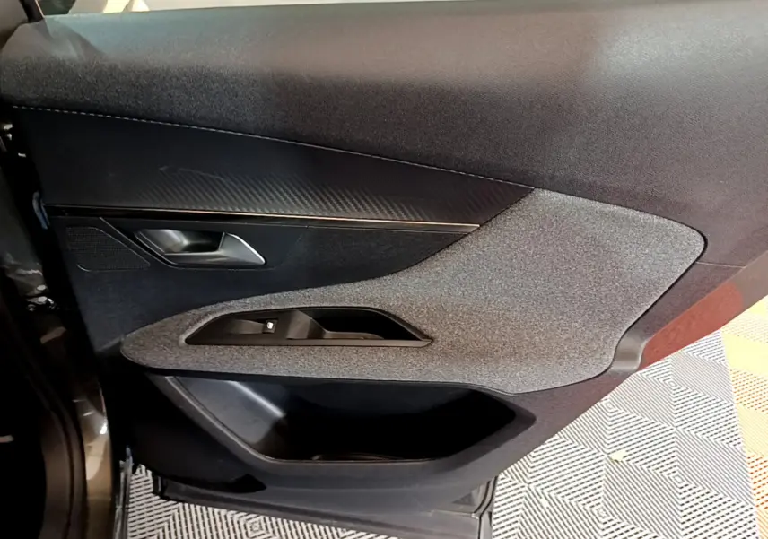 Détail de la porte côté gauche du Peugeot 3008 gris foncé, avec insert tissu et commandes des vitres intégrées.