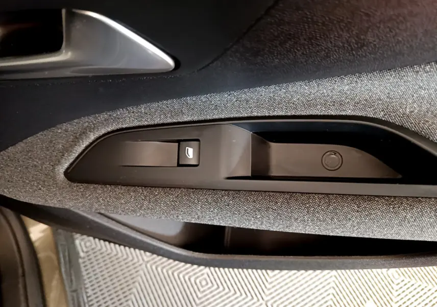 Gros plan sur la commande de lève-vitre côté conducteur, tissu gris foncé et poignée intérieure argentée du Peugeot 3008 2020.