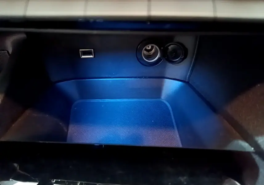 Rangement intérieur éclairé en bleu avec prise USB et prise 12V dans le Peugeot 3008 gris foncé 2020.
