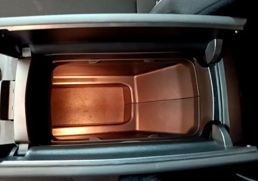 Vue en plongée sur le rangement central intérieur du Peugeot 3008 gris foncé, montrant un compartiment vide et éclairé.