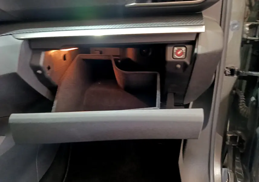 Gant de rangement ouvert côté passager intérieur d'un Peugeot 3008 gris foncé, éclairage intérieur visible