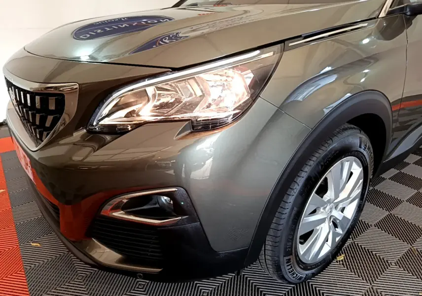 Vue 3/4 avant droit d'un Peugeot 3008 gris foncé avec phares allumés et jantes alliage visibles.