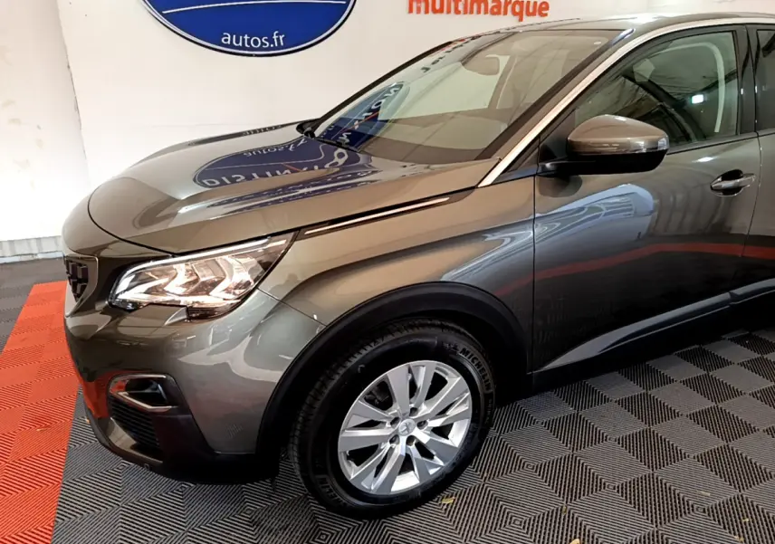 Vue 3/4 avant droit d'un Peugeot 3008 gris foncé avec phares LED allumés et jantes alliage visibles.