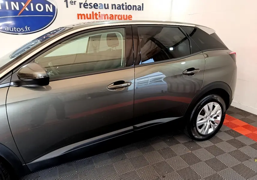 Profil côté gauche du Peugeot 3008 gris foncé 2020 dans un showroom avec sol à damier noir et rouge.