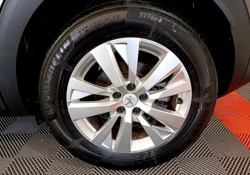 Gros plan sur la roue avant droite d’un Peugeot 3008 gris foncé, jante alliage à dix branches, pneu Michelin.