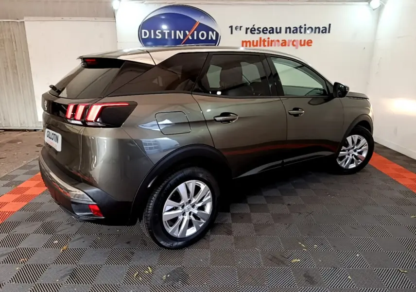 Vue 3/4 arrière droite d'un Peugeot 3008 gris foncé avec feux arrière LED et vitres teintées en intérieur showroom.