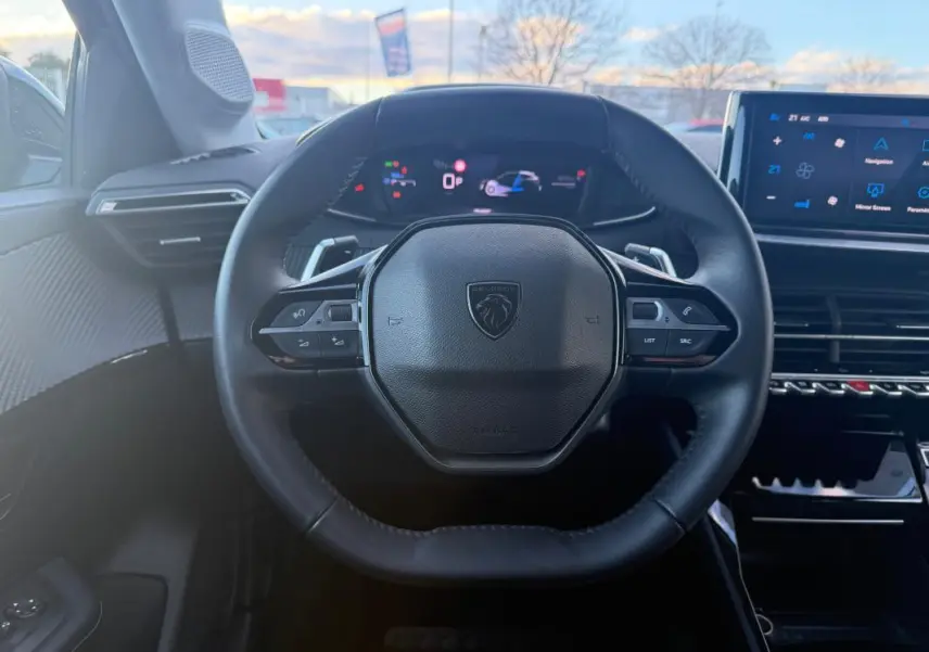 Vue intérieure centrée sur le volant cuir noir de la Peugeot 208 Hybrid 110, avec tableau de bord numérique et écran tactile.