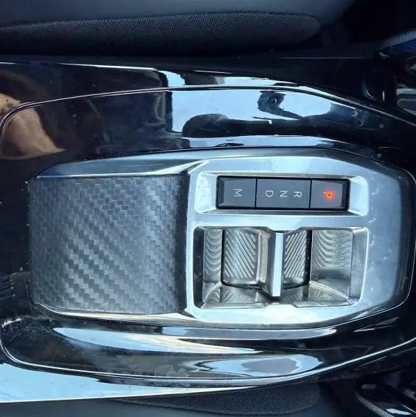 Vue rapprochée du levier de vitesses automatique noir avec finition carbone de la Peugeot 208 Hybrid 110 e-DCS6 Allure 2024.