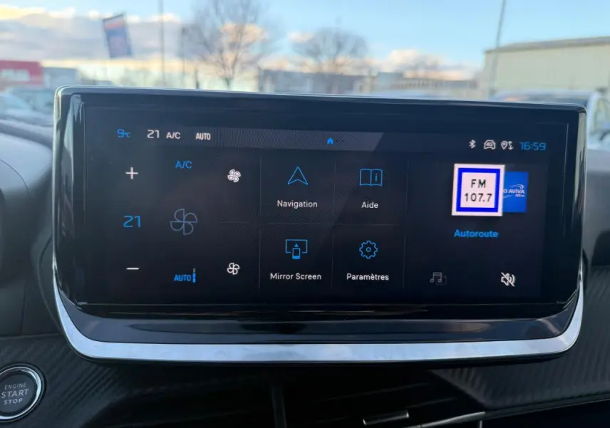 Écran tactile du tableau de bord de la Peugeot 208 Hybrid 110 noir, affichant la climatisation et la radio FM.
