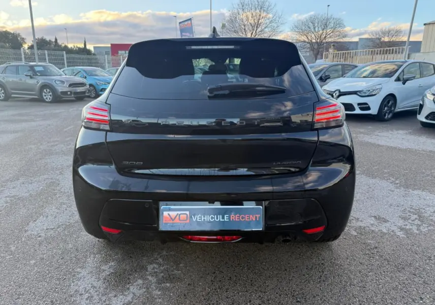 Vue arrière d'une Peugeot 208 Hybrid 110 noire de 2024, avec feux LED distinctifs et jantes alliage visibles.