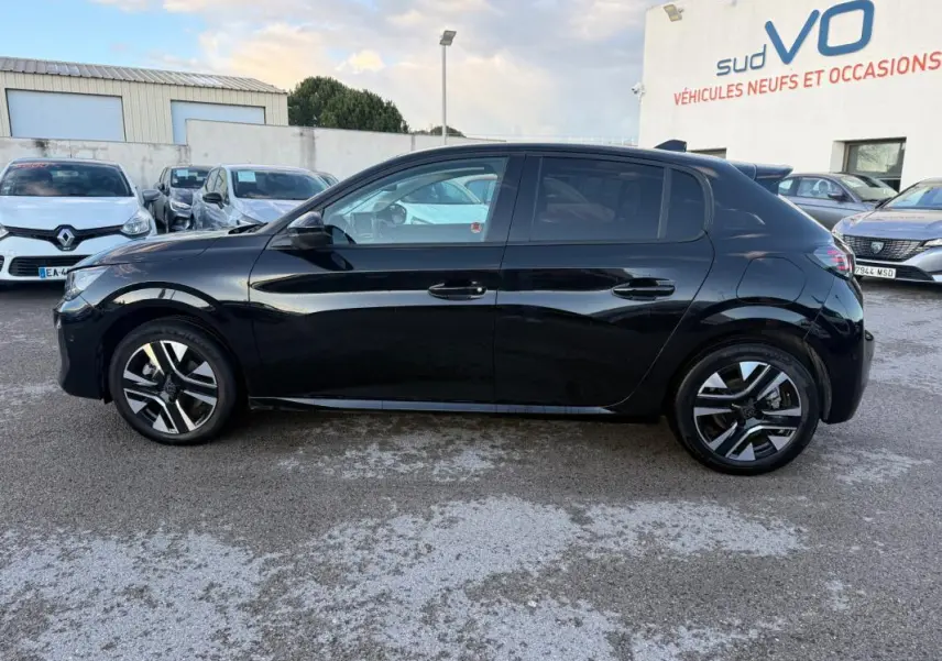 Profil droit d'une Peugeot 208 Hybrid 110 noire, avec jantes alliage 16 pouces et vitres teintées, stationnée en extérieur.