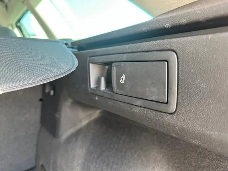 Détail du levier de rabattement des sièges dans le coffre du SEAT LEON ST 2025 gris métallisé, vue intérieure côté droit.