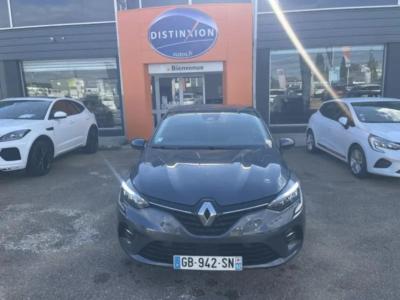 Vue avant d'une Renault Clio 1.6 E-Tech 140ch Business gris titanium garée devant un concessionnaire Distinxion
