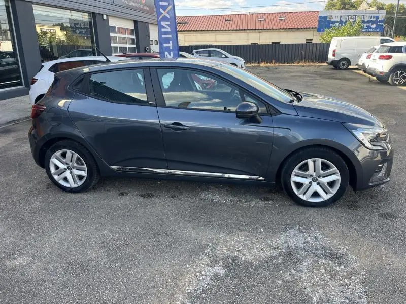 Profil côté gauche d'une Renault Clio 1.6 E-Tech 140ch Business 2021 en Gris Titanium avec jantes alliage visibles.