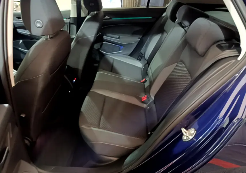 Vue côté gauche arrière de l'habitacle d'une Volkswagen Golf bleue 2022, sièges arrière en tissu gris foncé.