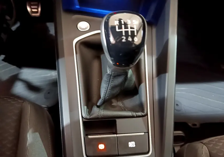 Le levier de vitesse manuel noir de la Volkswagen Golf 2022, vu de dessus, avec bouton de frein à main électrique allumé.