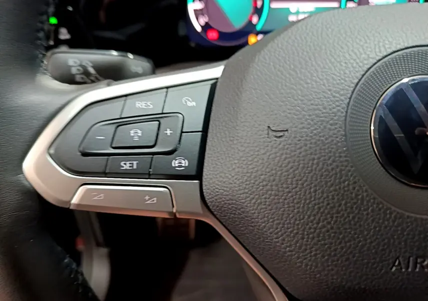 Gros plan sur le côté gauche du volant cuir noir de la Volkswagen Golf 1.0 TSI 2022 avec commandes multifonctions.