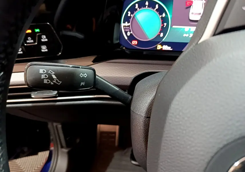 Gros plan sur le commodo gauche du volant d'une Volkswagen Golf 2022, avec tableau de bord numérique coloré en arrière-plan.