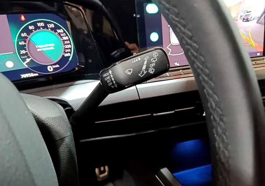 Gros plan sur le commodo d'essuie-glace et tableau de bord numérique d'une Volkswagen Golf bleue de 2022.