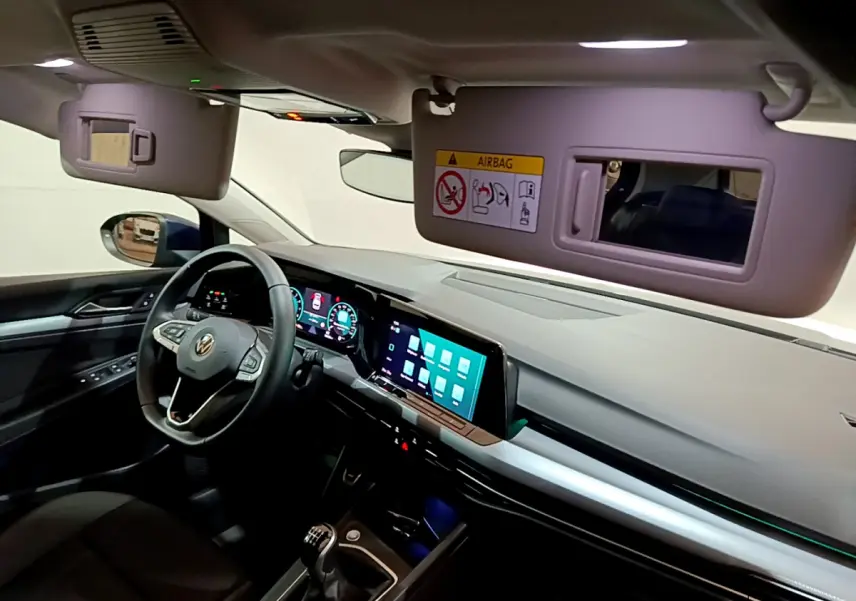 Vue intérieure avant droite de la Volkswagen Golf 1.0 TSI Active 2022, volant cuir, écran tactile et miroir pare-soleil ouvert.