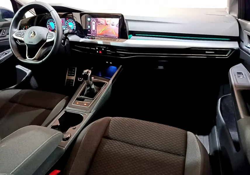 Vue intérieure avant droite de la Volkswagen Golf 1.0 TSI 2022 avec tableau de bord numérique et éclairage d'ambiance bleu