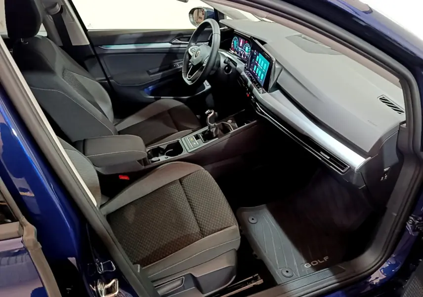 Intérieur côté conducteur d'une Volkswagen Golf bleu 2022, avec tableau de bord numérique et boîte manuelle visible.