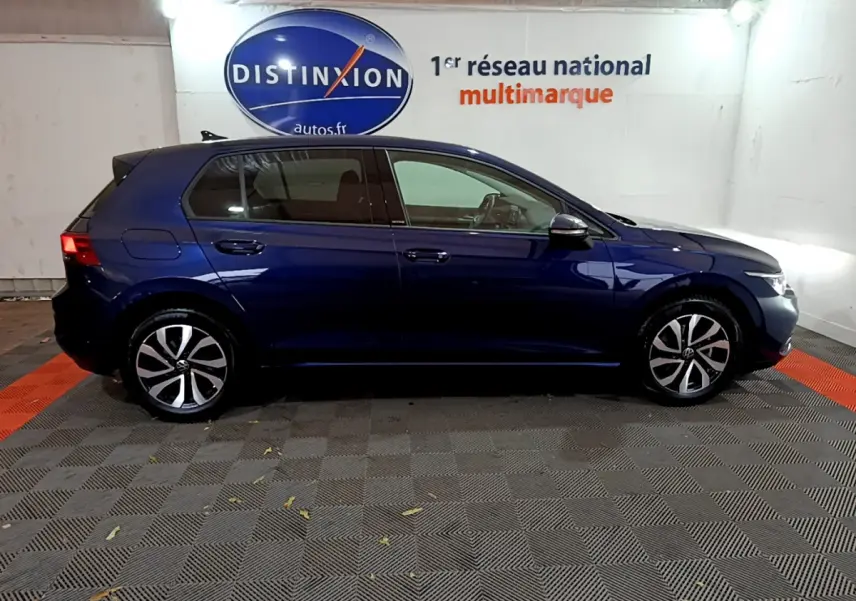 Profil droit d'une Volkswagen Golf bleu foncé 2022 garée en intérieur avec jantes alliage distinctives.