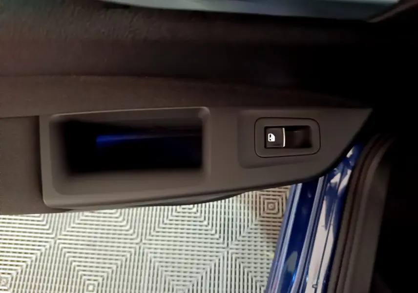 Poignée intérieure de porte côté gauche d'une Volkswagen Golf 2022 bleu, avec bouton de verrouillage intégré.