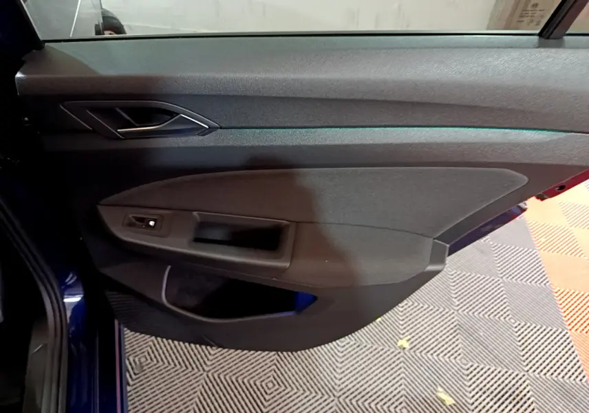 Vue rapprochée de la porte côté gauche de la Volkswagen Golf 1.0 TSI Active 2022 en bleu, avec poignée et commande de vitre.