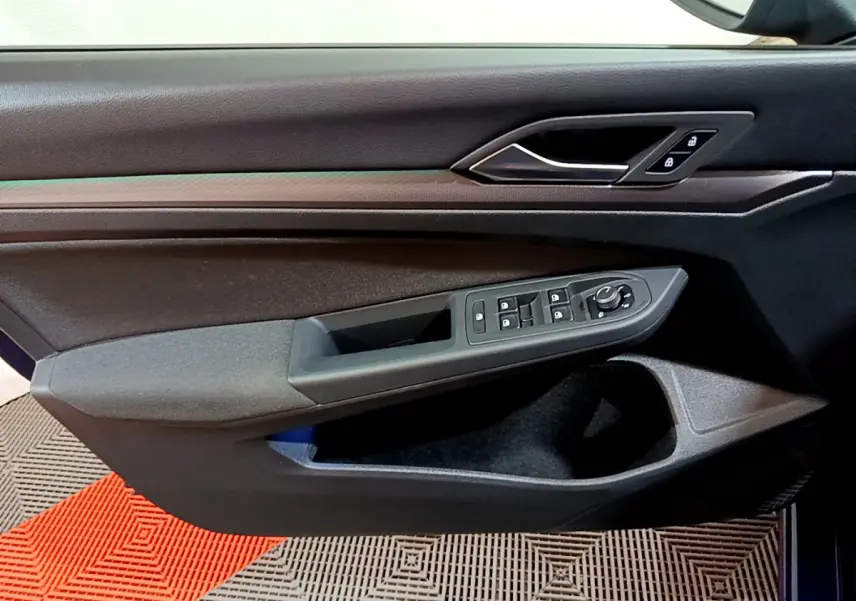 Vue rapprochée de la porte avant gauche noire de la Volkswagen Golf 1.0 TSI 2022 avec commandes de vitres et verrouillage.