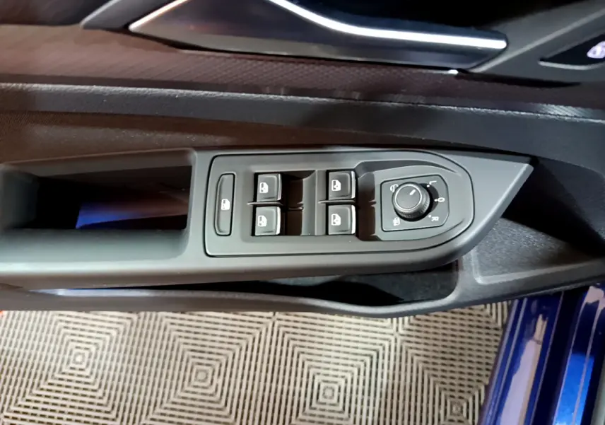 Gros plan sur la commande des vitres et rétroviseurs côté conducteur d'une Volkswagen Golf bleu 2022.