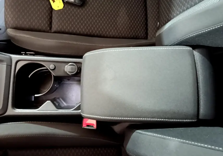 Vue plongeante sur la console centrale noire avec accoudoir et zone de recharge par induction d'une Volkswagen Golf bleue 2022.