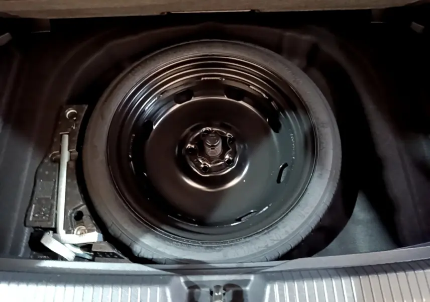 Roue de secours noire et outil de changement dans le coffre d'une Volkswagen Golf 1.0 TSI 2022.