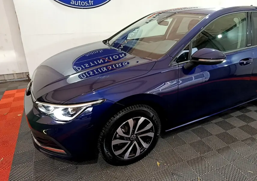 Vue 3/4 avant droit d'une Volkswagen Golf bleu nuit avec phares LED allumés et jantes alliage distinctives.