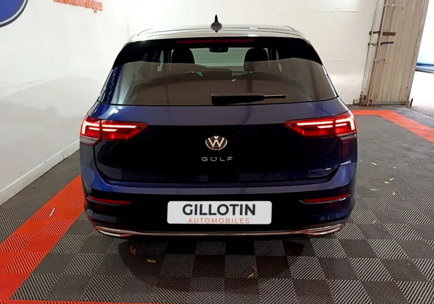 Vue arrière d'une Volkswagen Golf bleue 2022 avec feux LED allumés dans un garage intérieur.