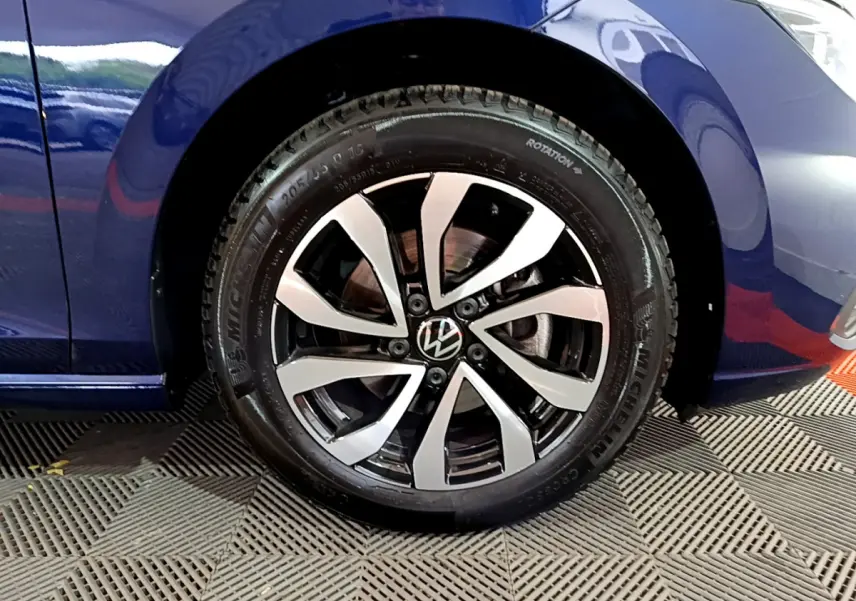 Gros plan sur la roue avant droite d'une Volkswagen Golf bleu 2022, avec jante alliage bicolore et pneu Michelin.