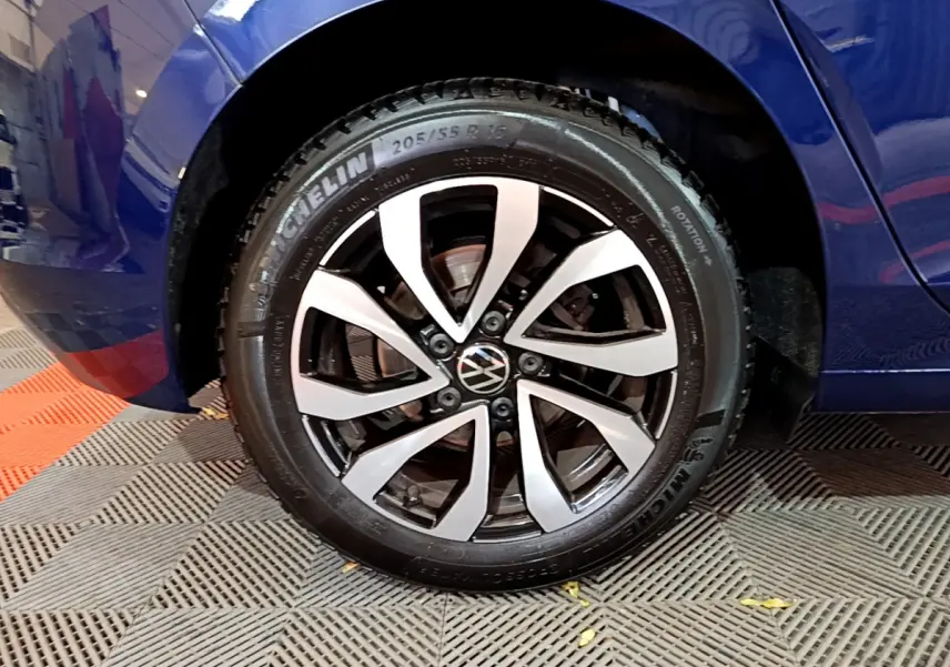 Gros plan sur la roue avant gauche d'une Volkswagen Golf bleu 2022 avec jante alliage bicolore et pneu Michelin.