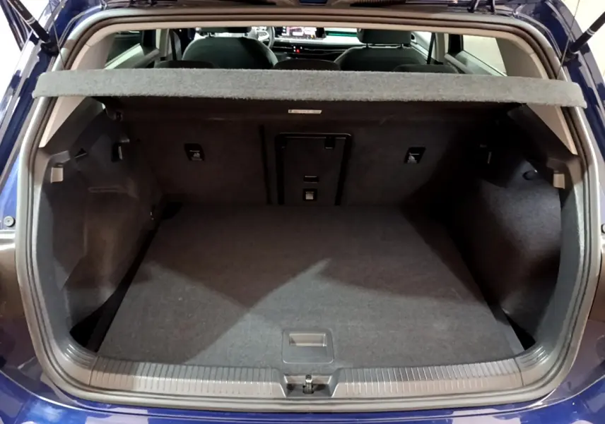 Coffre ouvert vu de l'arrière d'une Volkswagen Golf 1.0 TSI bleu, montrant l'espace de chargement vide et la tablette de séparation.
