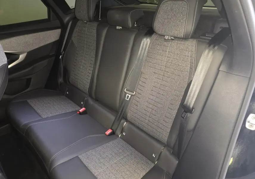 Vue intérieure côté droit sur la banquette arrière tissu gris et cuir noir du Peugeot 3008 noir hybride 2025.