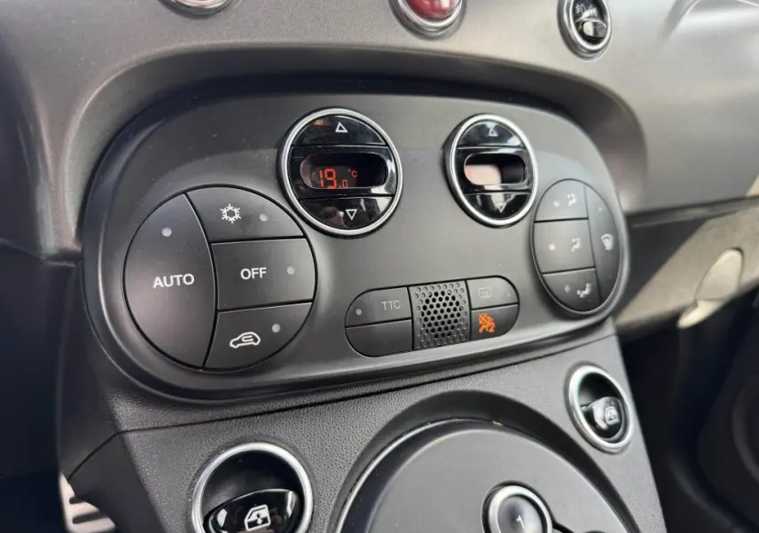Vue rapprochée du tableau de bord noir de l'Abarth 500 blanc, montrant les commandes de climatisation et ventilation digitales.