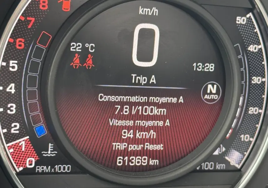 Gros plan sur le tableau de bord numérique de l'Abarth 500 blanc, affichant la vitesse, consommation et kilométrage.