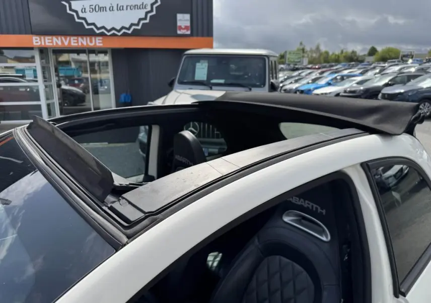 Toit ouvrant ouvert vu de dessus sur l'ABARTH 500 blanc avec sièges sport en cuir marqués ABARTH.