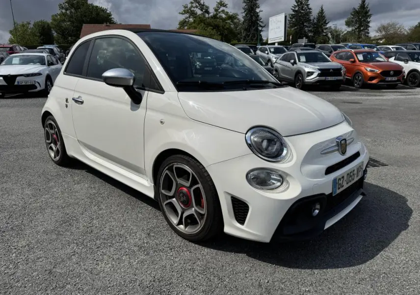 ABARTH 500 blanc en 3/4 avant droit avec jantes sport et coques de rétroviseurs chromées sur parking.