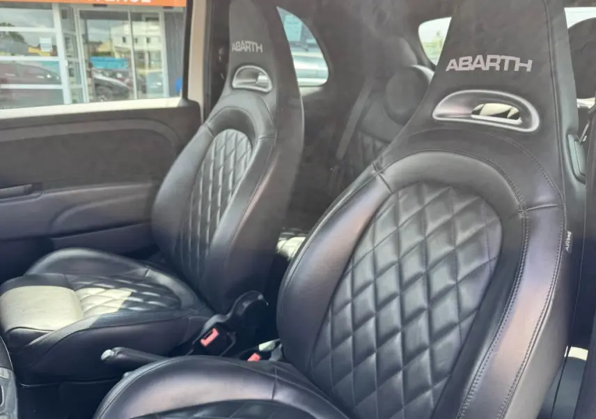 Gros plan sur les sièges sport en cuir noir avec logo ABARTH brodé, intérieur de l'Abarth 500 blanc 2021.