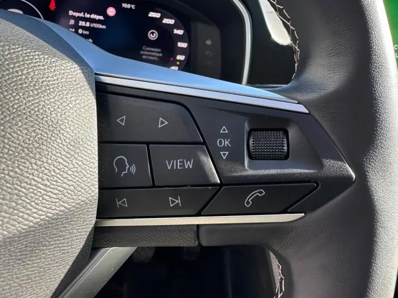 Gros plan sur les commandes multifonctions à droite du volant du SEAT LEON ST 2025, avec affichage numérique en arrière-plan.