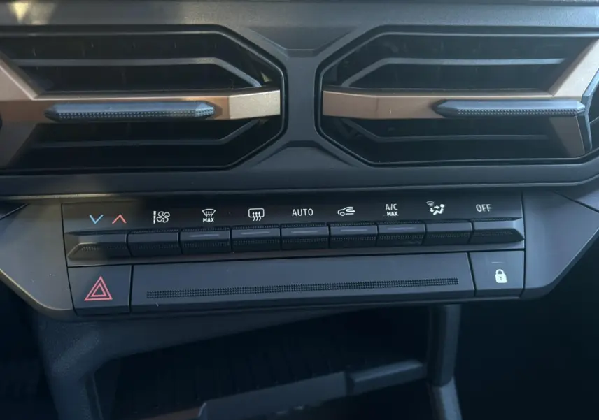 Détail de la console centrale du Dacia Duster 2026 gris, montrant les commandes de climatisation et les aérateurs noirs.