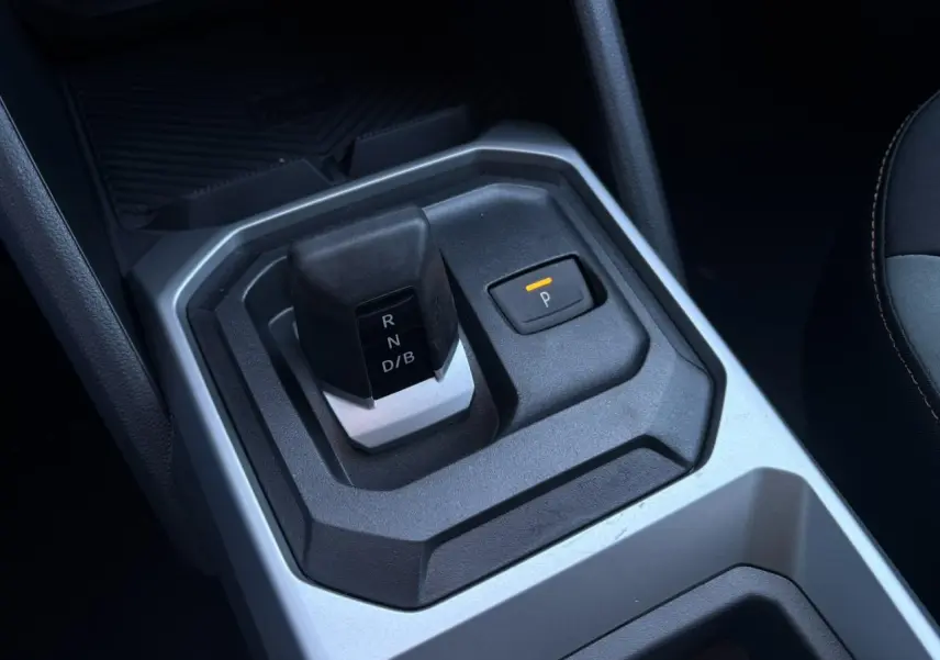 Gros plan sur la commande de boîte automatique et le bouton de parking du Dacia Duster gris Schiste, intérieur moderne.