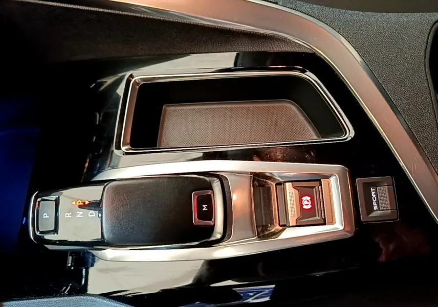 Gros plan sur la console centrale du Peugeot 3008 2020, avec levier de boîte auto noir et bouton mode Sport visible.