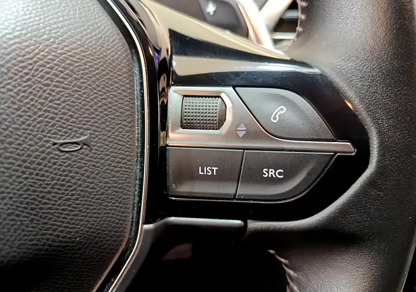 Gros plan sur les commandes gauche du volant cuir du Peugeot 3008 blanc, boutons LIST, SRC et téléphone.