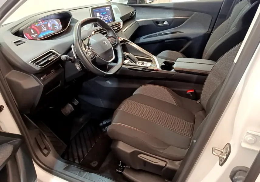 Intérieur côté conducteur du Peugeot 3008 blanc 2020, volant cuir, tableau de bord digital et sièges tissu gris.